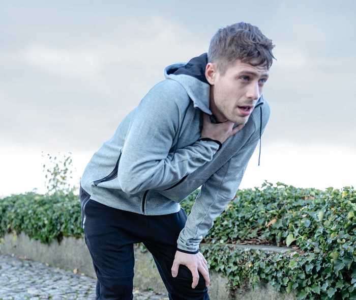 Asthmapatient Alex fasst sich nach dem Joggen an den Hals und holt tief Luft