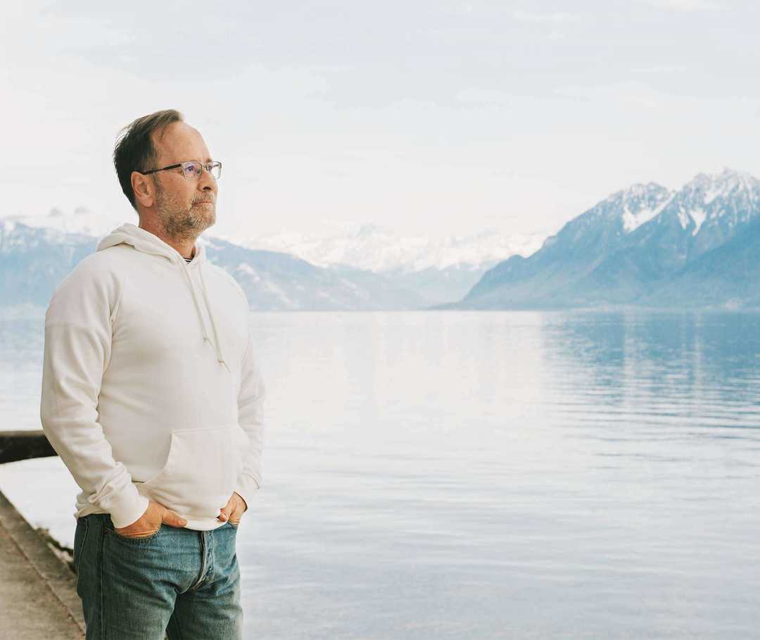 Mann steht am Wasser und schaut in die Ferne