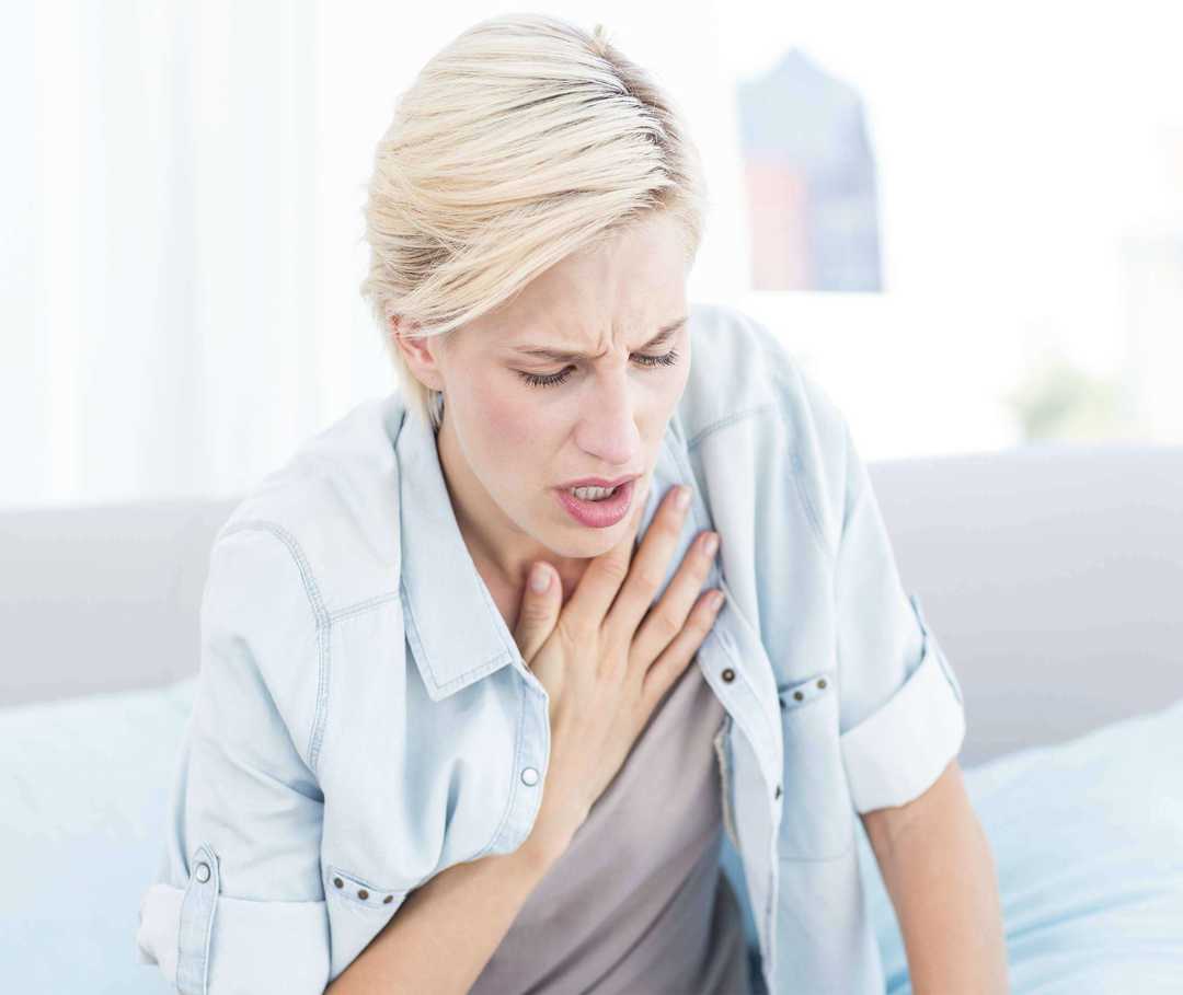 Frau fasst sich an den Hals und holt Luft