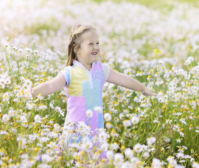 Mädchen spielt im Blumenfeld