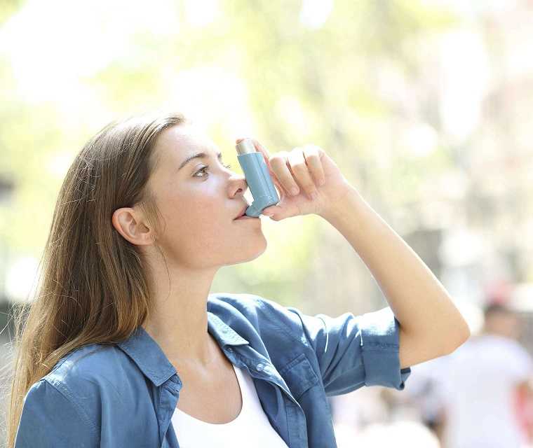 Junge Frau benutzt Asthmaspray
